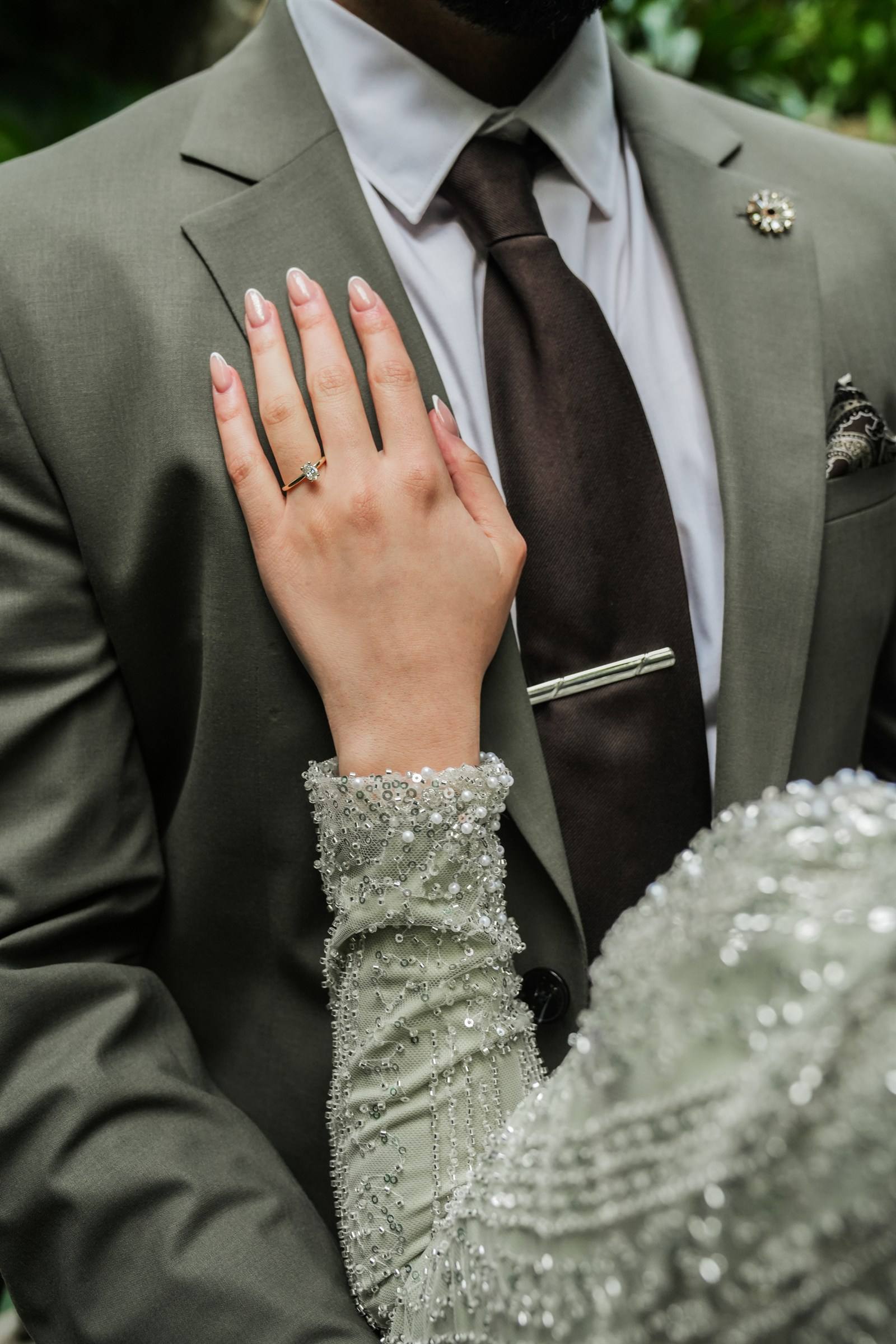 Hand der Verlobten mit Ring auf dem Sakko ihres Partners