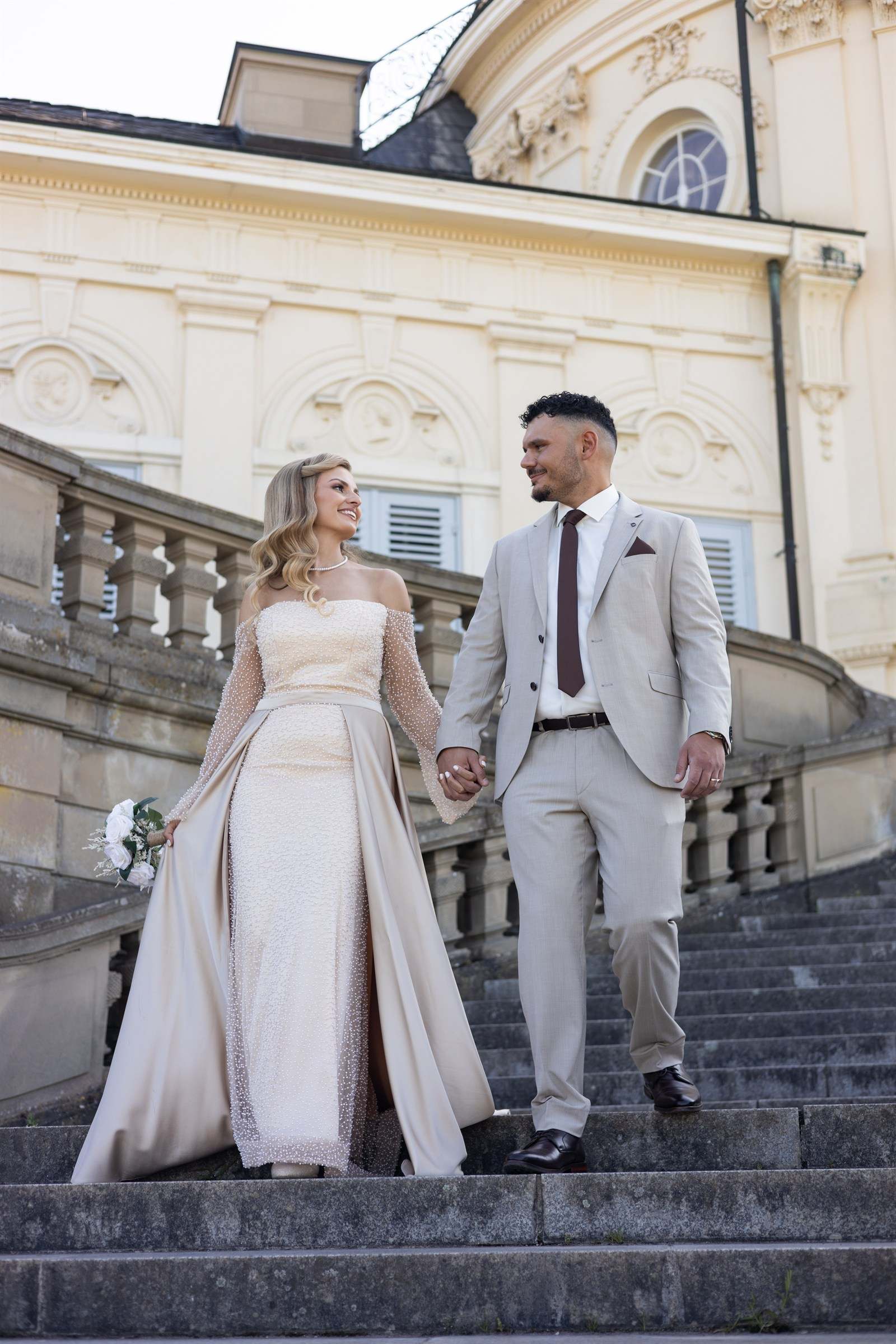 Paar geht Hand in Hand eine Schlosstreppe hinunter