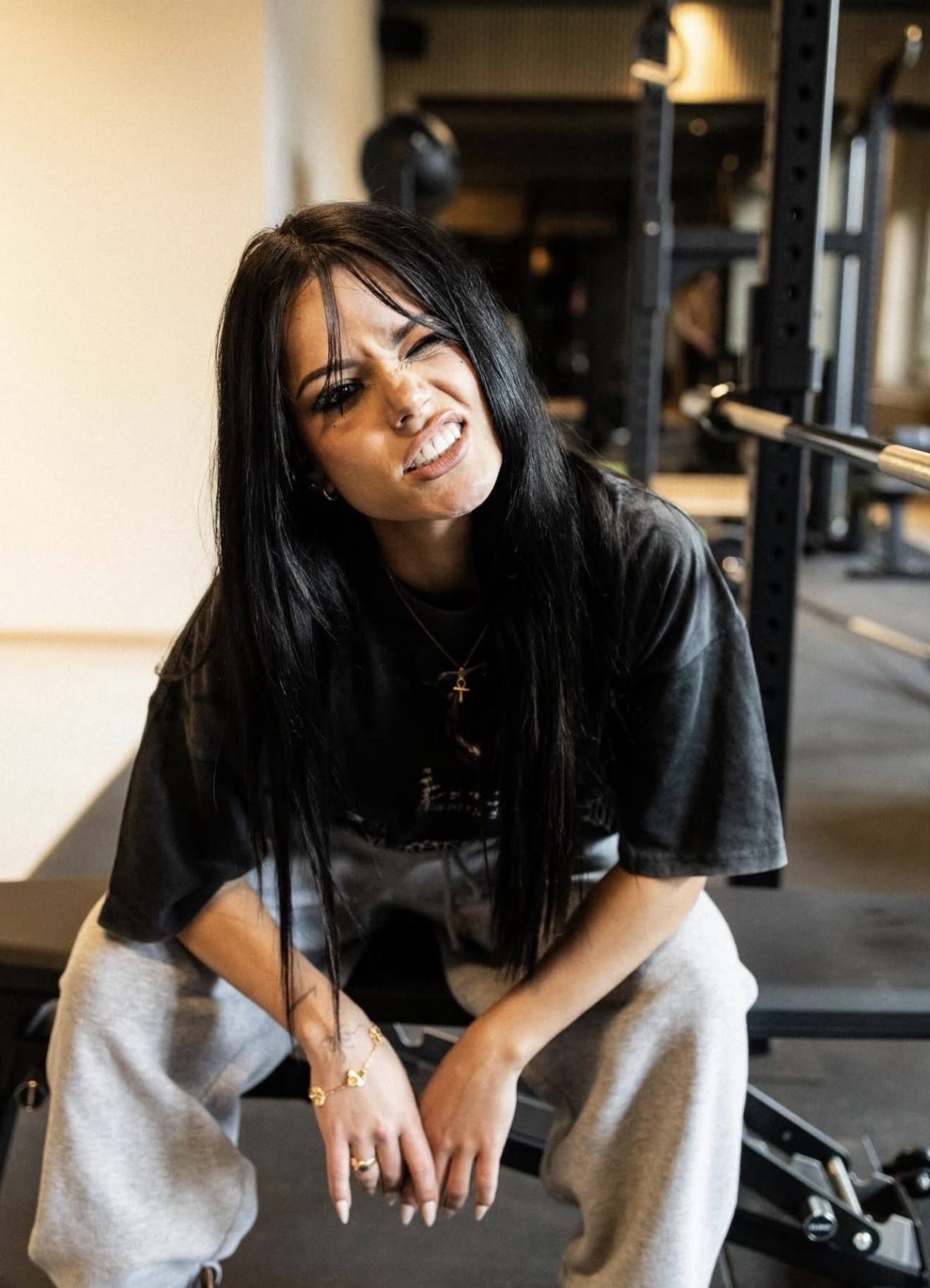 Frau im Oversize-Shirt sitzt in einem Gym