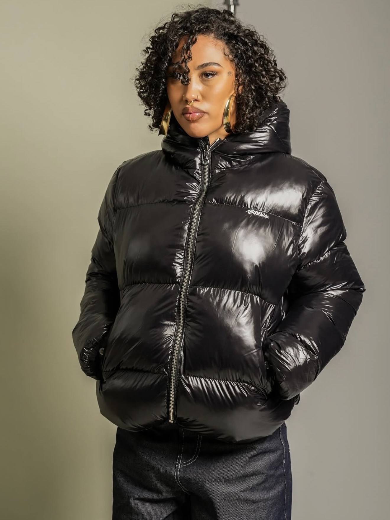 Frau in glänzender Pufferjacke vor hellem Hintergrund